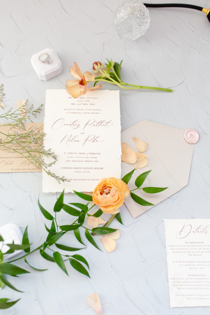 Custom stationery in a flatlay with orange pastel flowers for Cypress Grove Estate House Wedding