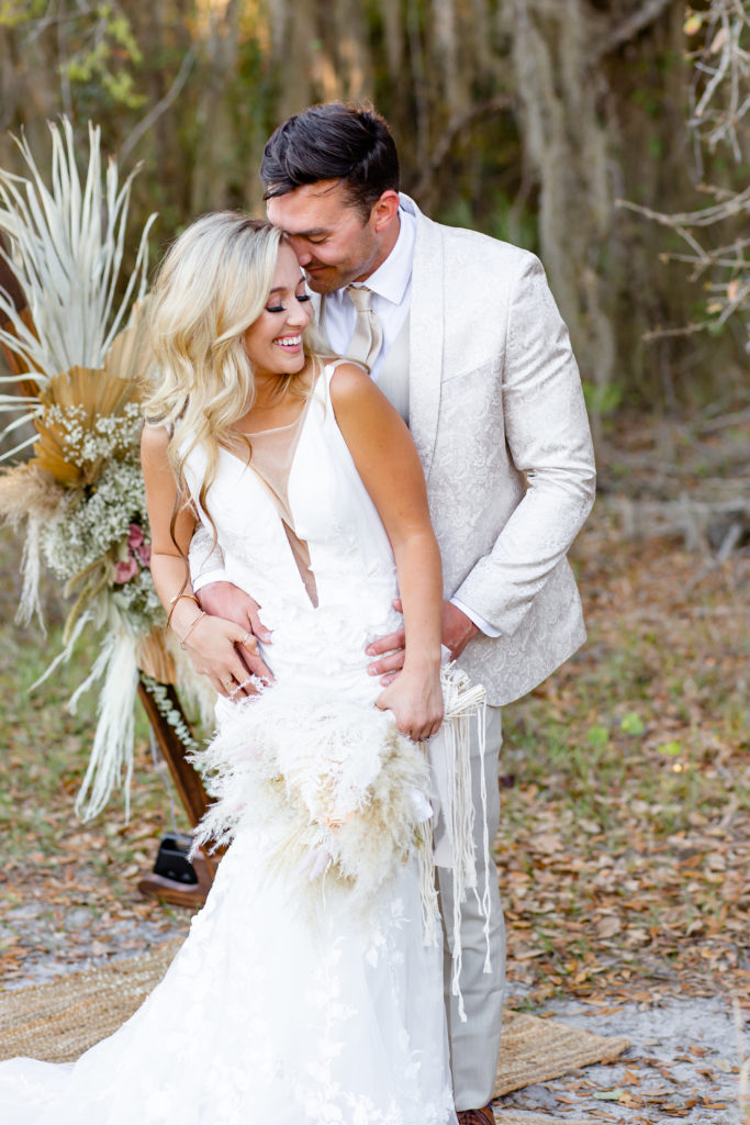 Bride holds pampas grass bouquet while groom embraces her