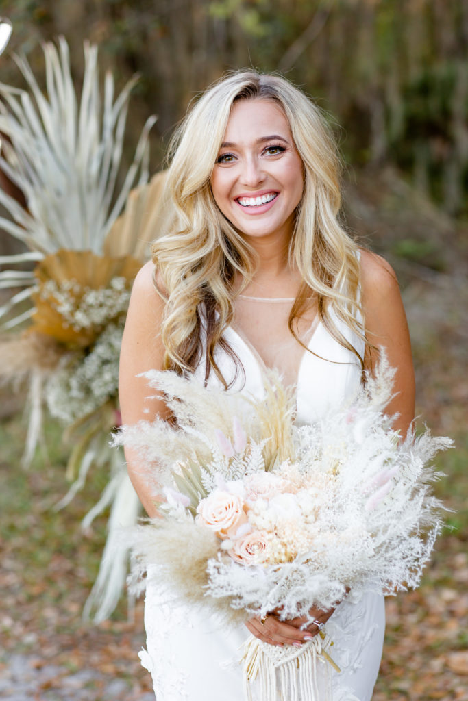 Bride smiles while holding a pampas grass bouquet