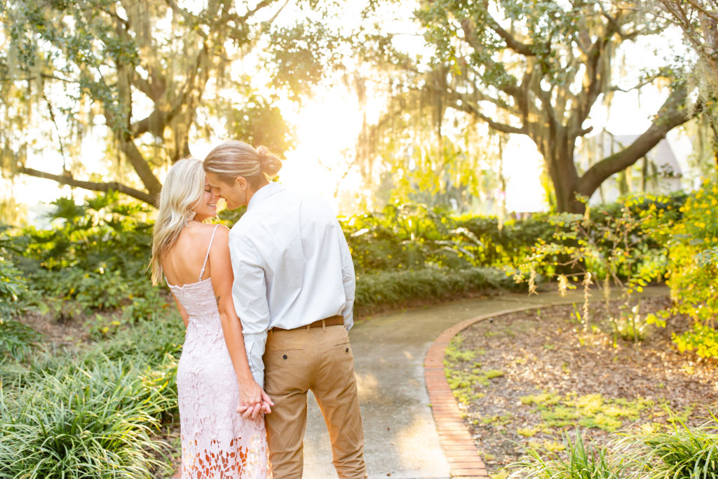 Cypress Grove Park Engagement Photos — Couple wearing white goes in for a kiss with the sun setting behind them