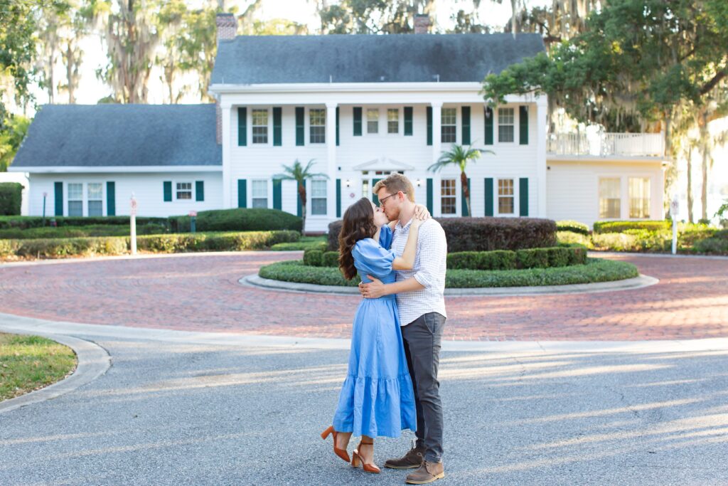 Couple kisses in front of Cypress Grove Estate House for their engagement photos at Cypress Grove Park in Orlando, Florida