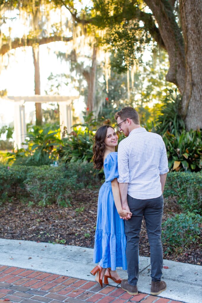 Couple stands holding hands in front of Cypress Grove Estate House for their engagement photos at Cypress Grove Park in Orlando, Florida