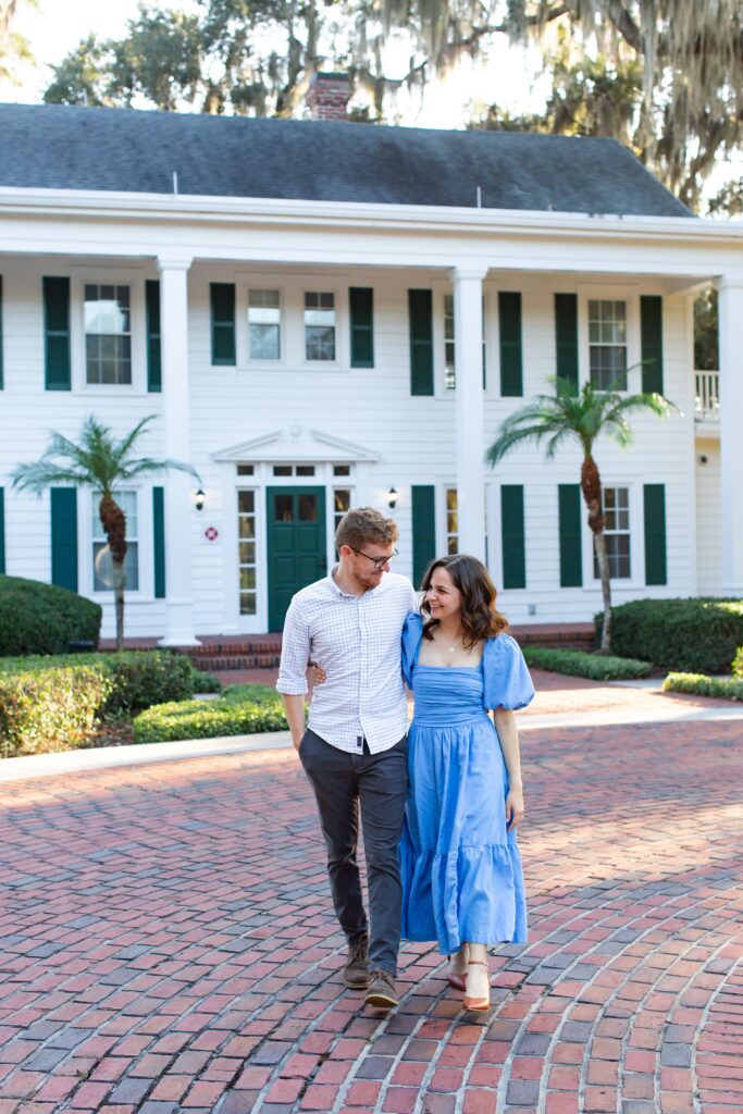 Couple walks in front of Cypress Grove Estate House for their engagement photos at Cypress Grove Park in Orlando, Florida