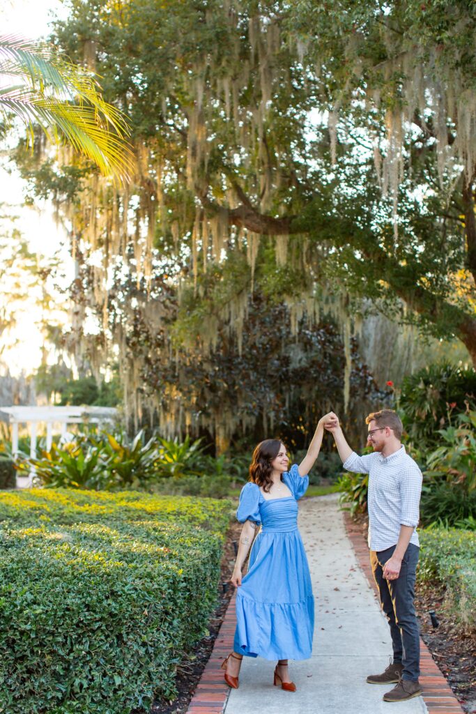 Guy twirls girl for their engagement photos at Cypress Grove Park in Orlando, Florida