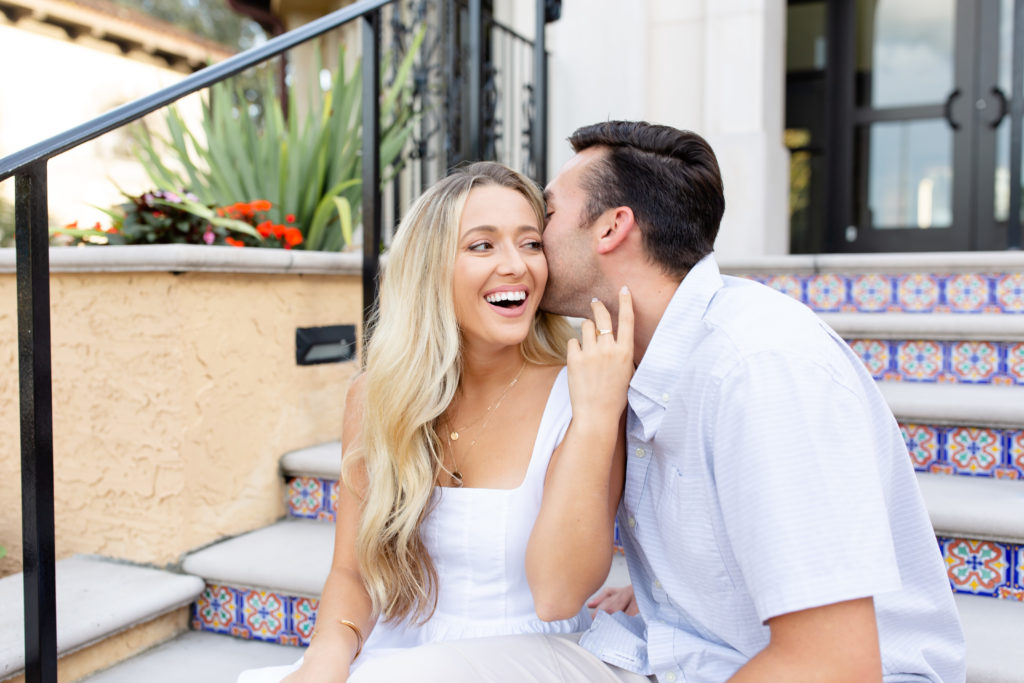 Rollins College engagement photo - a young couple sits on the stairs of their college campus