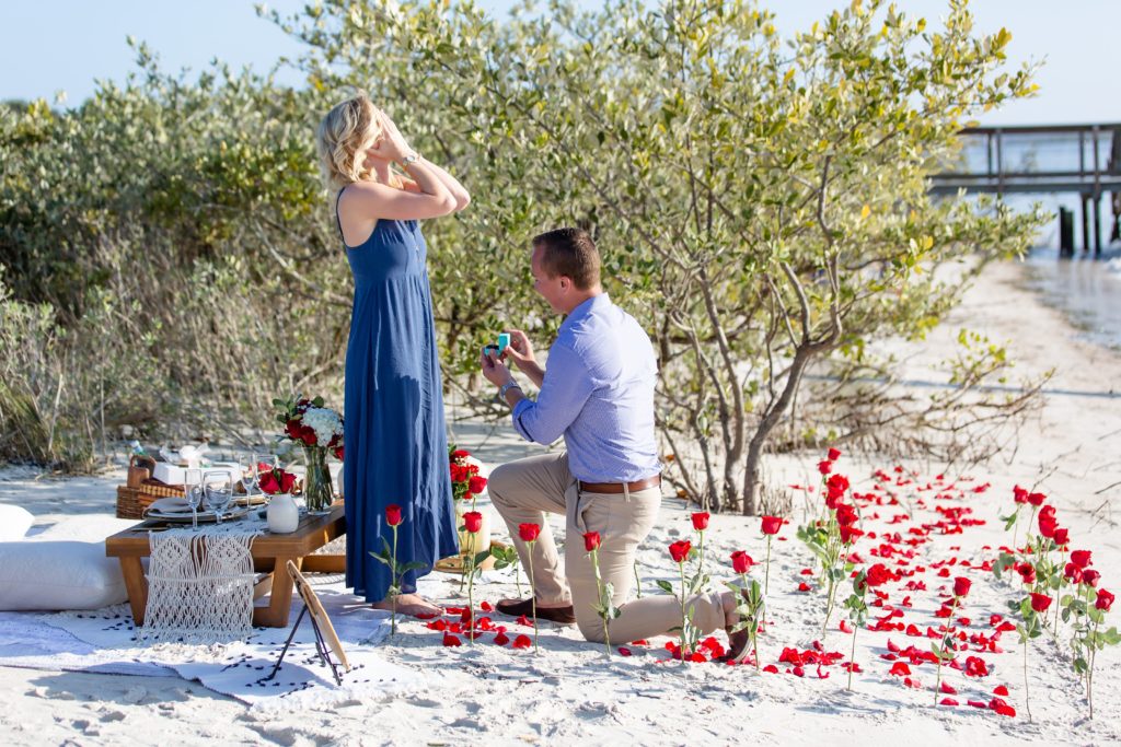 Surprise beach proposal in Florida with a rose petal aisle and sand under their feet
