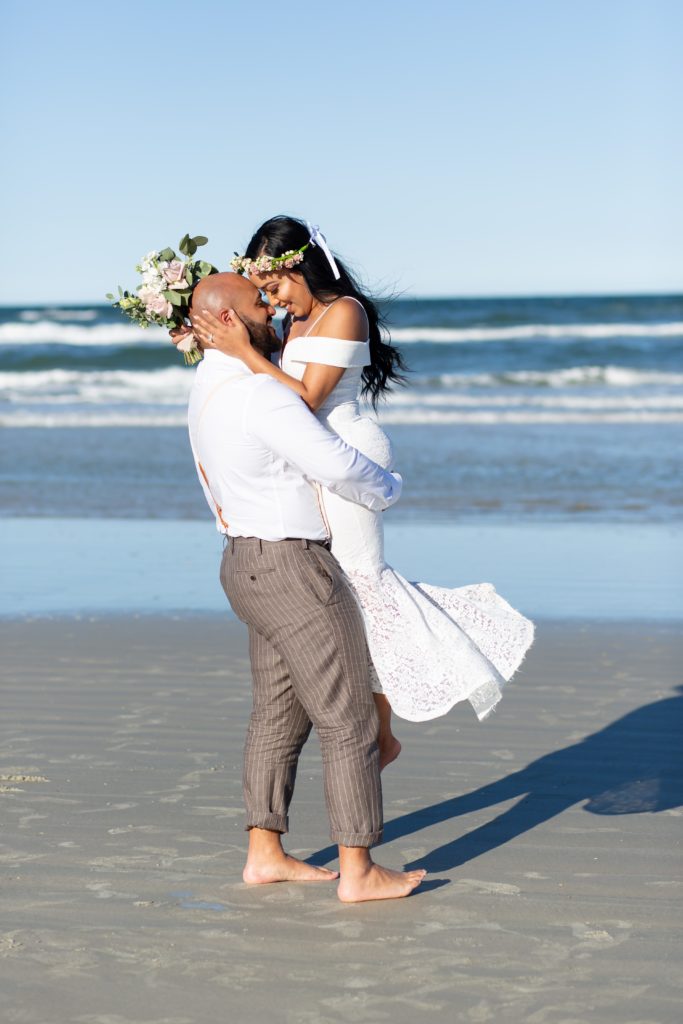 New Smyrna Beach Elopement Photo — Groom picking up Bride and spinning her on the beach
