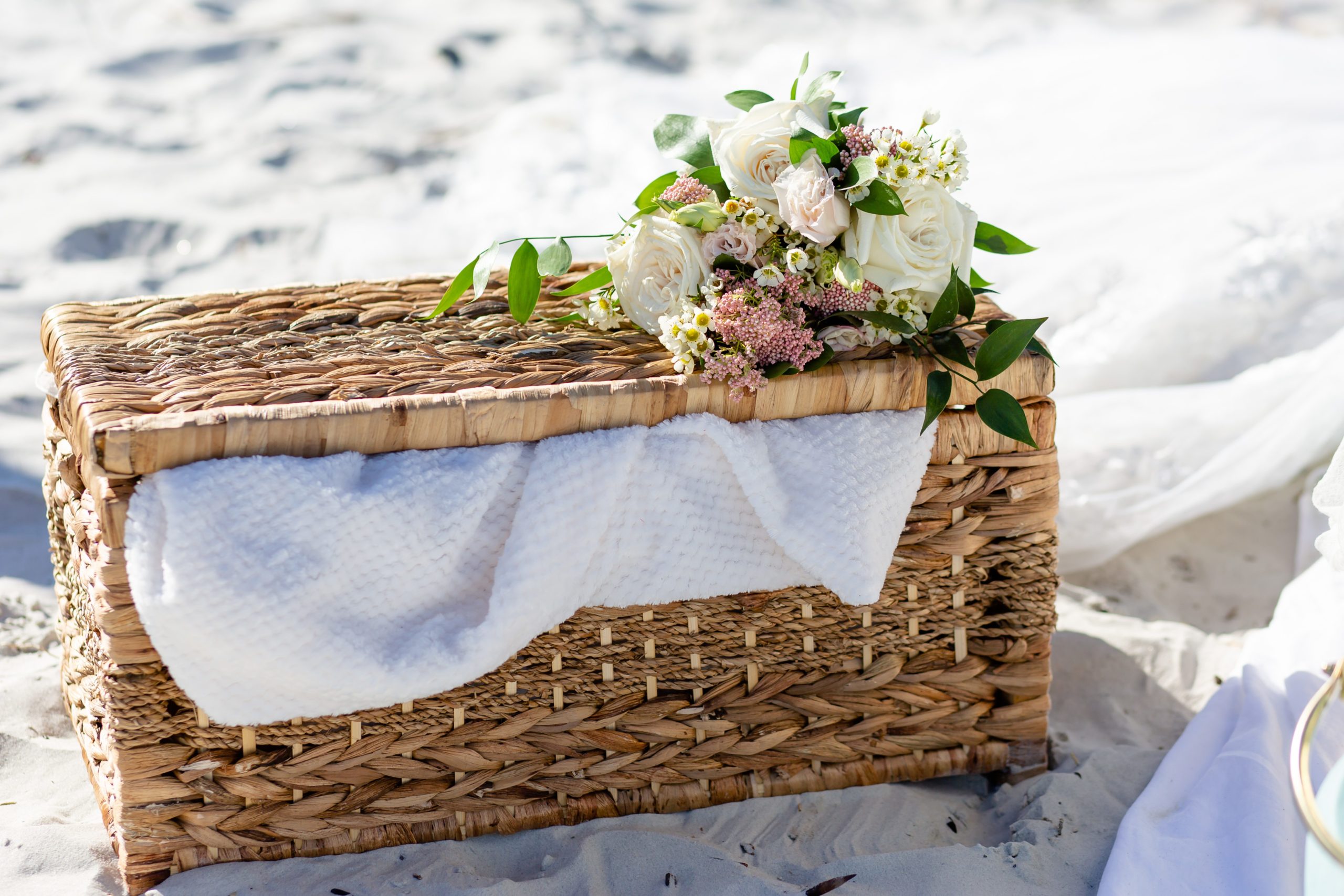 Elopement picnic on the beach with a bouquet sitting on a basket in the sand