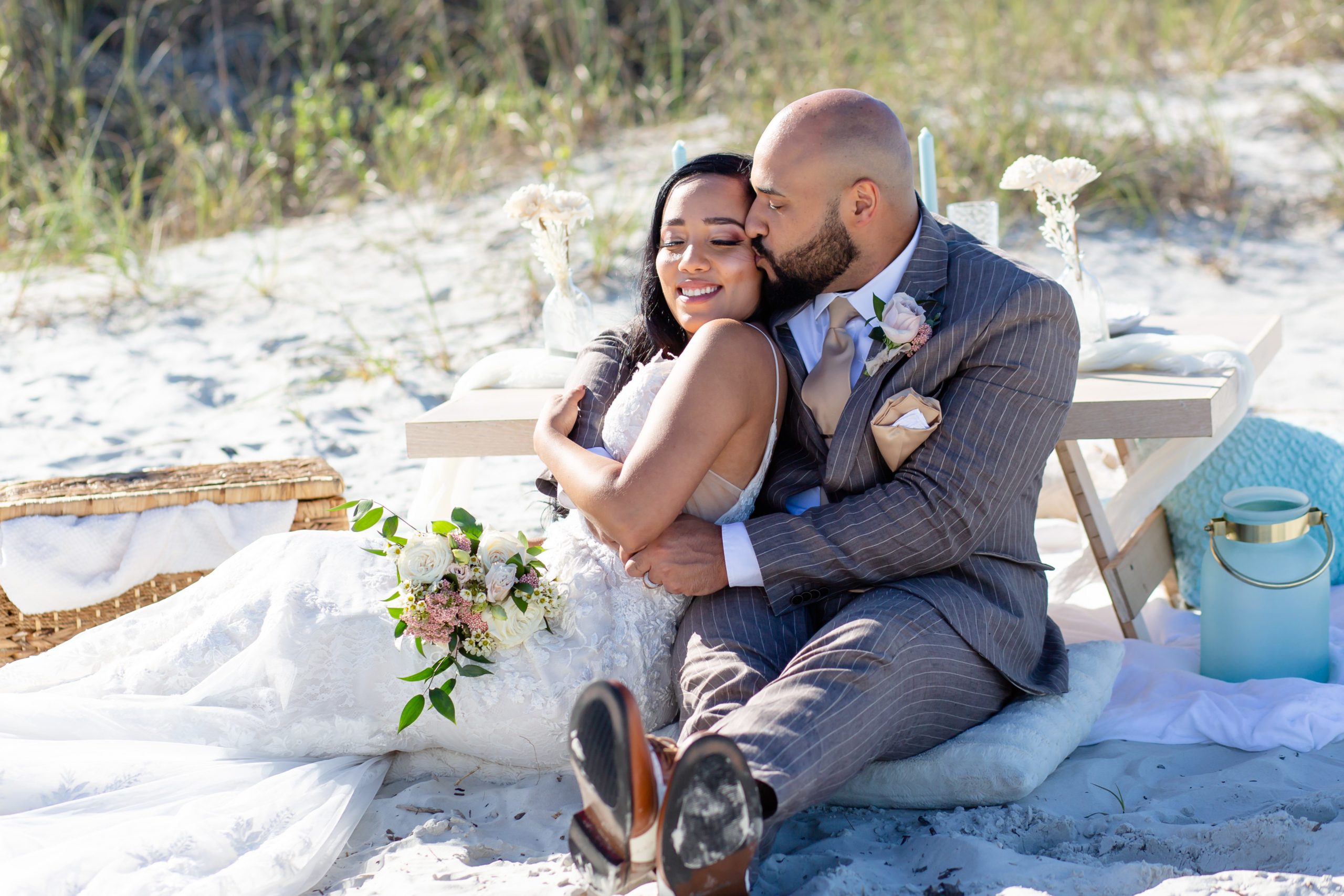 Bride and groom sit next to their pastel blue elopement picnic tablescape