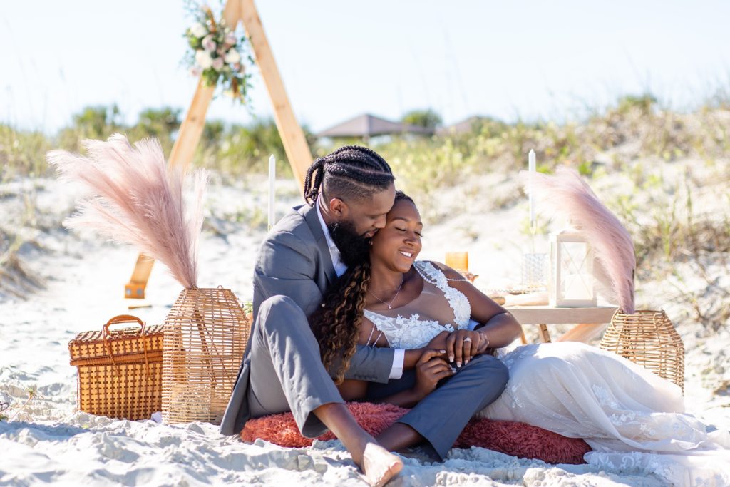 New Smyrna Beach Wedding Photo — Bride & Groom cuddling at pop up picnic on the beach