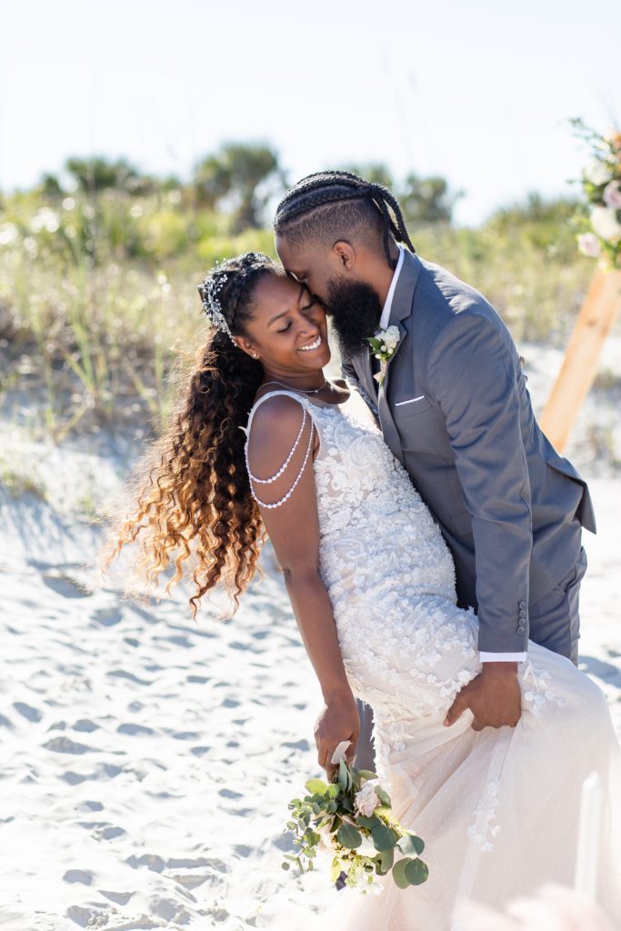 New Smyrna Beach Wedding Photo — Groom kissing Bride's cheek after wedding ceremony on the beach