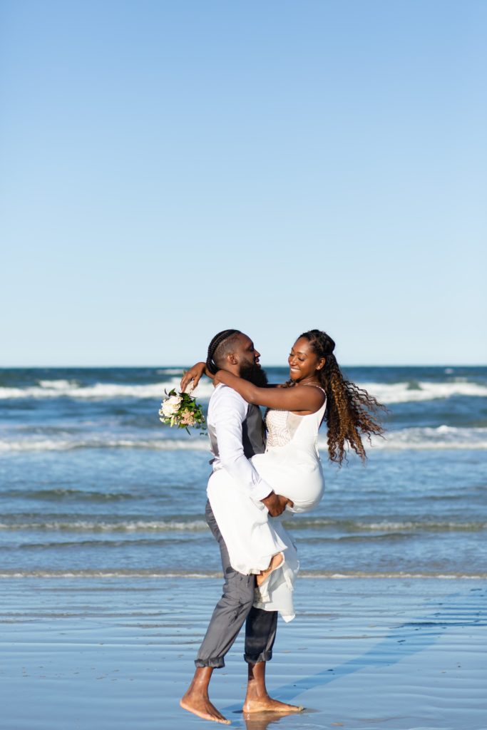 New Smyrna Beach Wedding Photo — Groom picking up Bride on the beach
