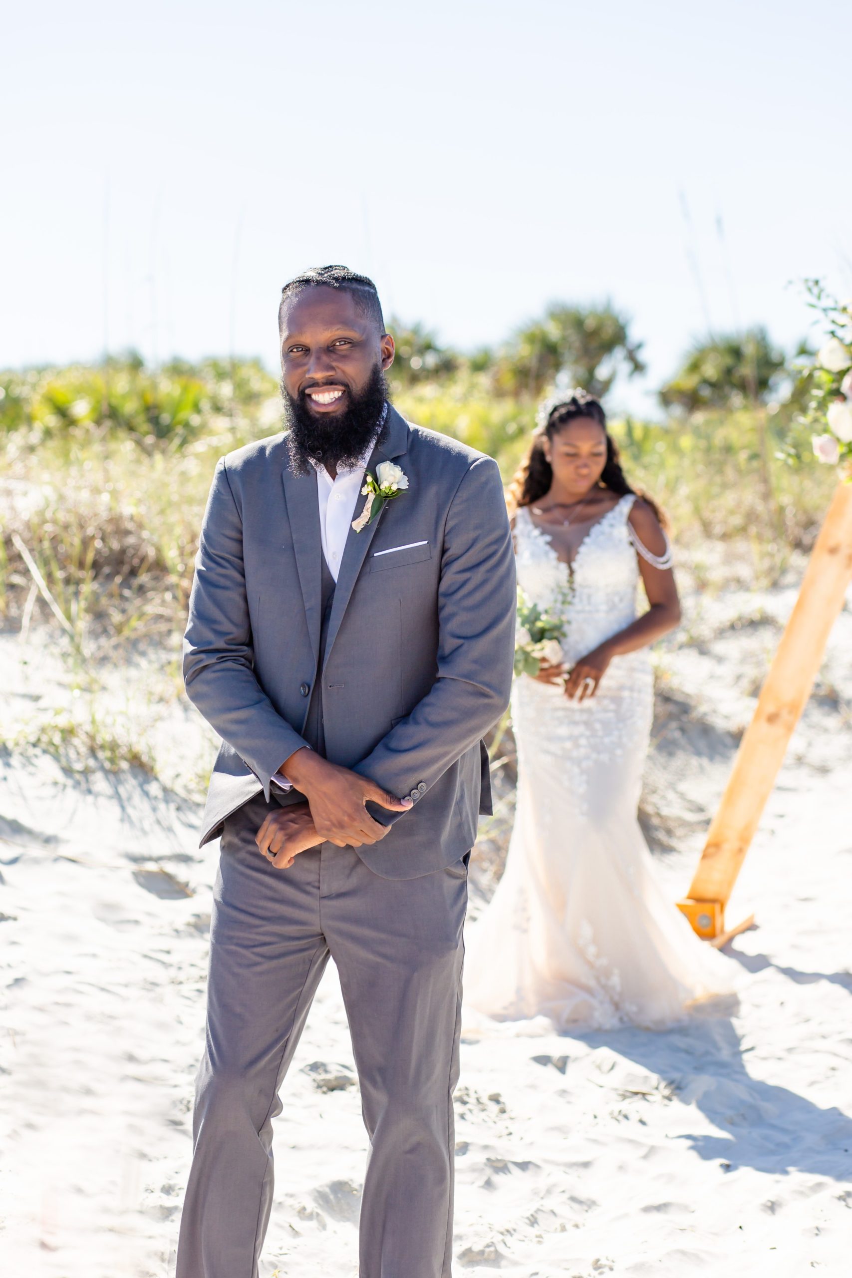 Groom smiles at the camera just before his first look on the beach