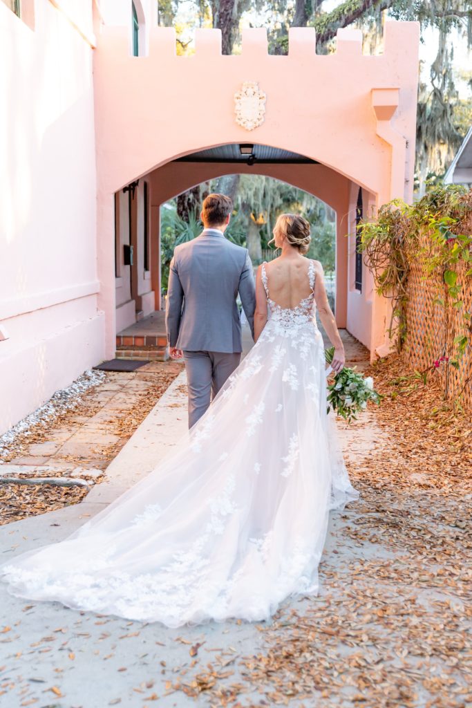 Pillars' Castle Wedding Photo — Bride and Groom walking in pink castle