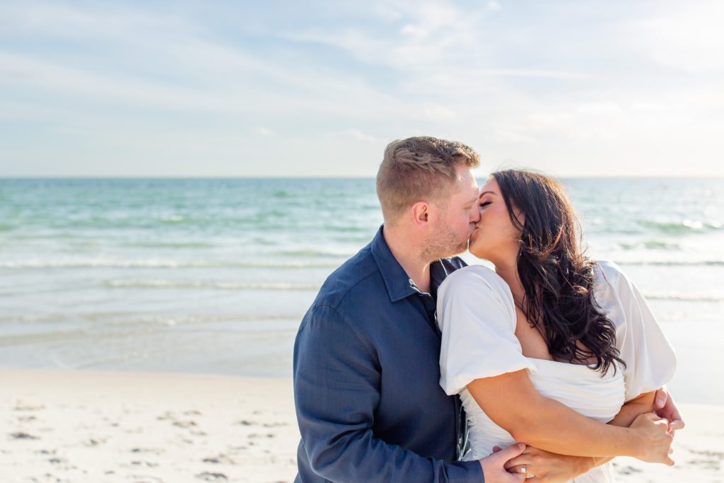 Couple kisses in front of the ocean during their Florida engagement photo session