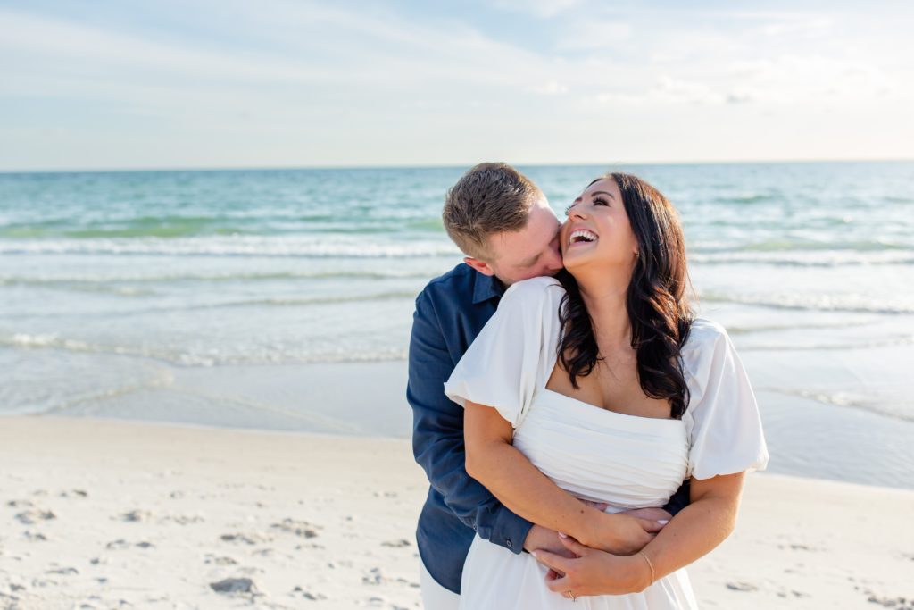 Florida engagement photos on the beach — Couple kissing and laughing on the beach