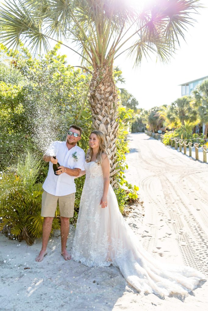 Popping champagne at their island elopement