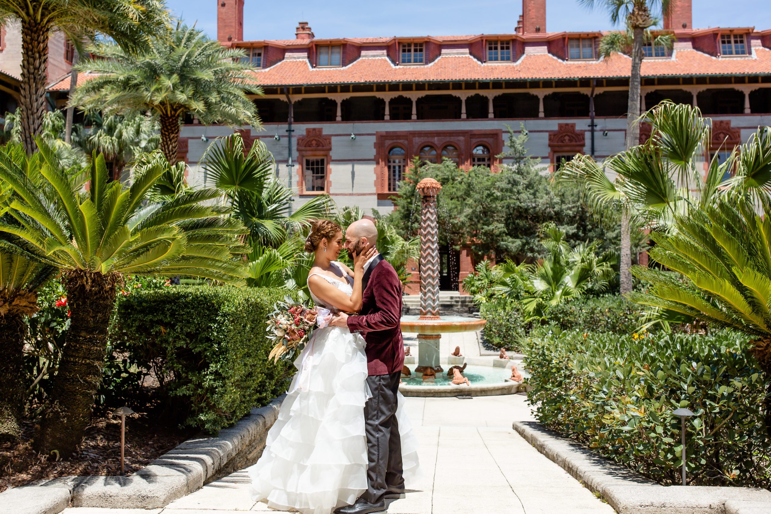 Flagler College Wedding Photo — Bride and Groom kissing in front of beautiful fountain and palm trees in courtyard
