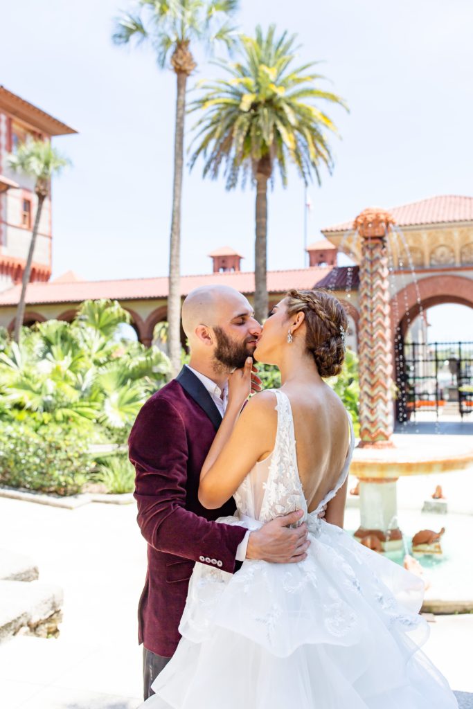 Flagler College Wedding Photo — Bride and Groom kissing in front of beautiful fountain and palm trees in courtyard