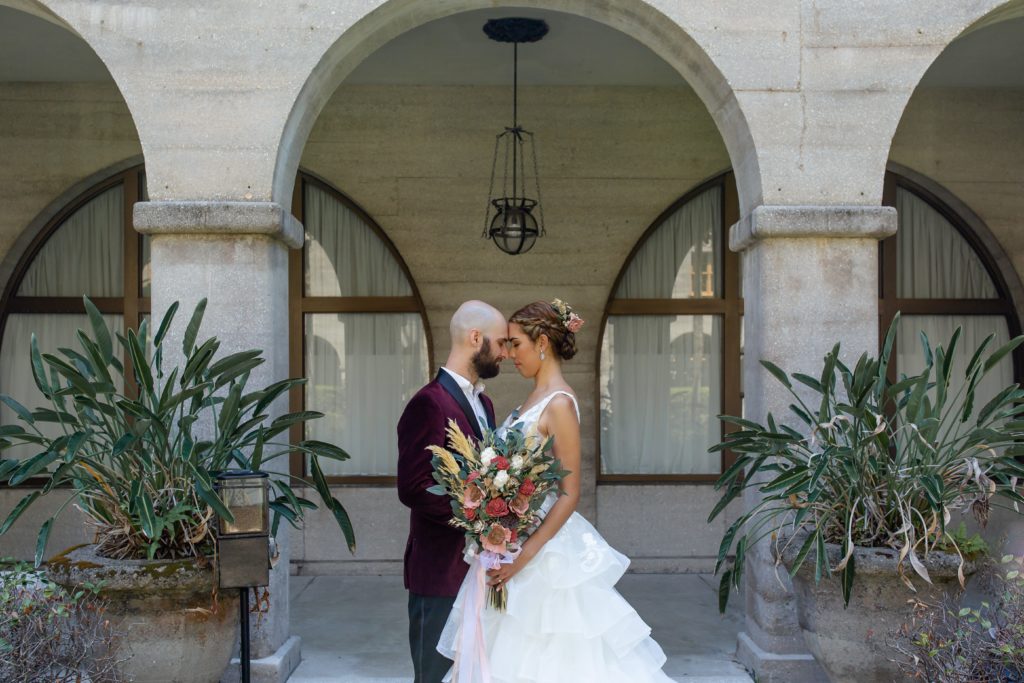 Lightner Museum courtyard wedding photo of the couple forehead to forehead beneath gray arches in the architecture