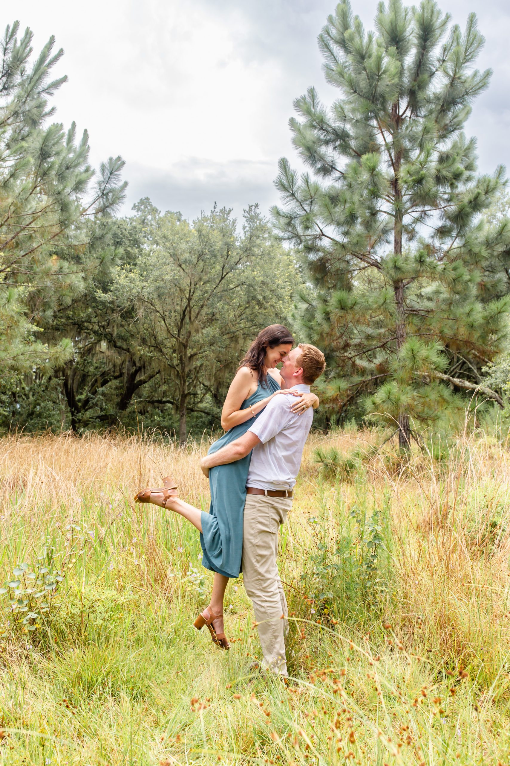 Lake Runnymede Engagement Photo — Guy lifting girl in field