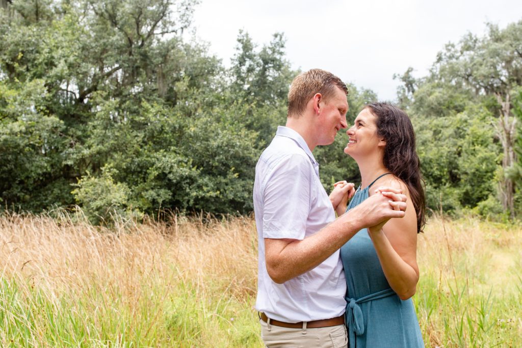 Lake Runnymede Engagement Photo — Couple holding hands and smiling in field
