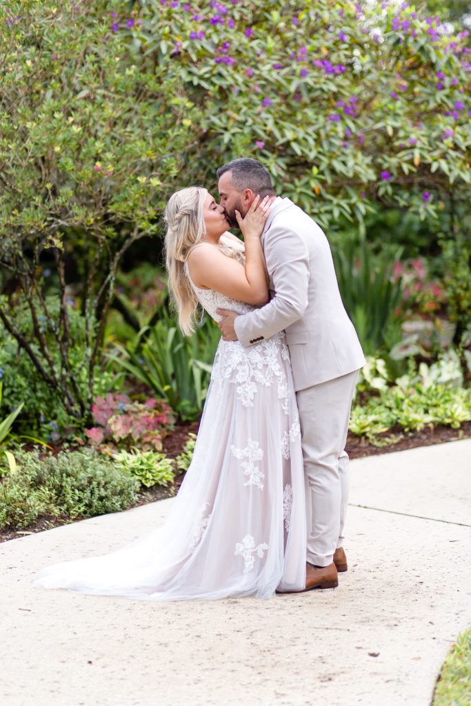 Leu Gardens Wedding Photos in Orlando, FL — Bride and Groom kissing in front of purple flowers