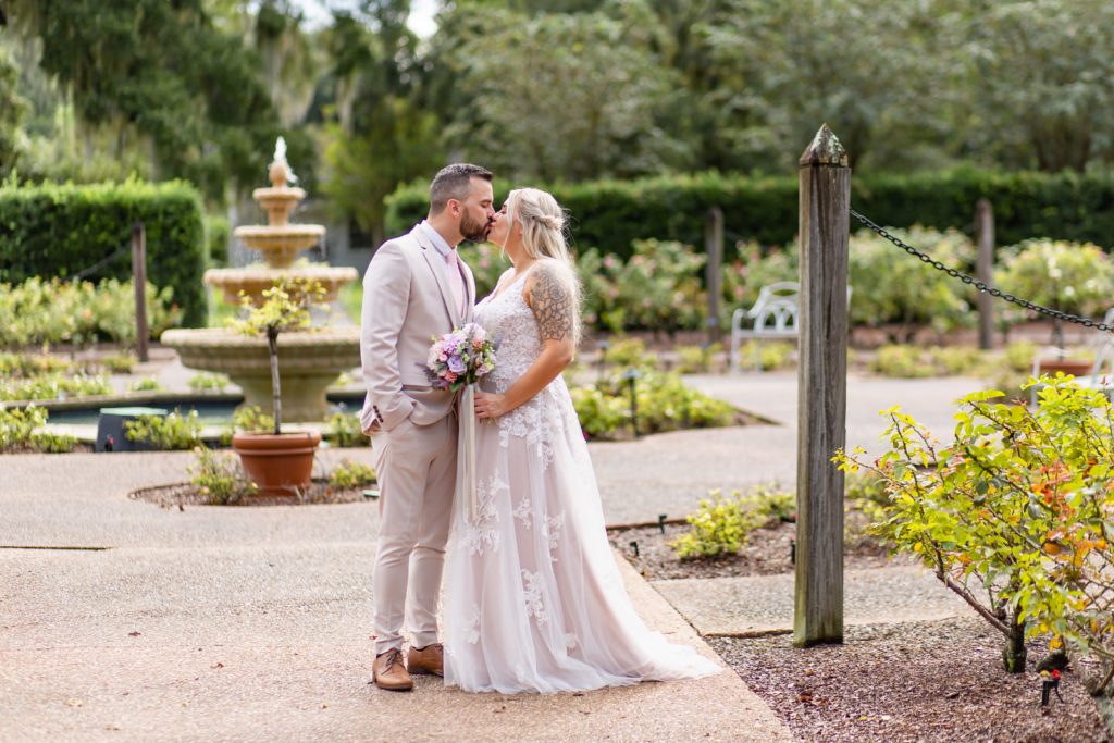 Leu Gardens Wedding Photos in Orlando, FL — Bride and Groom kissing in front of fountain in rose garden