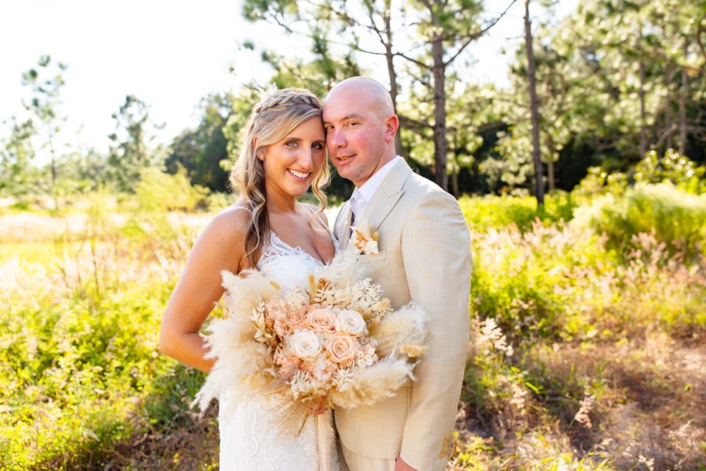 Lake Louisa Wedding Photos in Orlando, FL — Groom and Bride holding a dried bridal bouquet standing in field