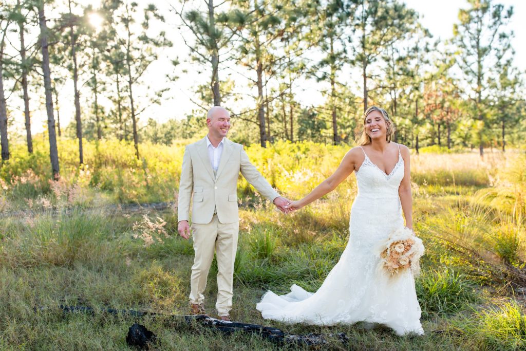 Lake Louisa Wedding Photos in Orlando, FL — Groom and Bride holding a dried bridal bouquet walking in field