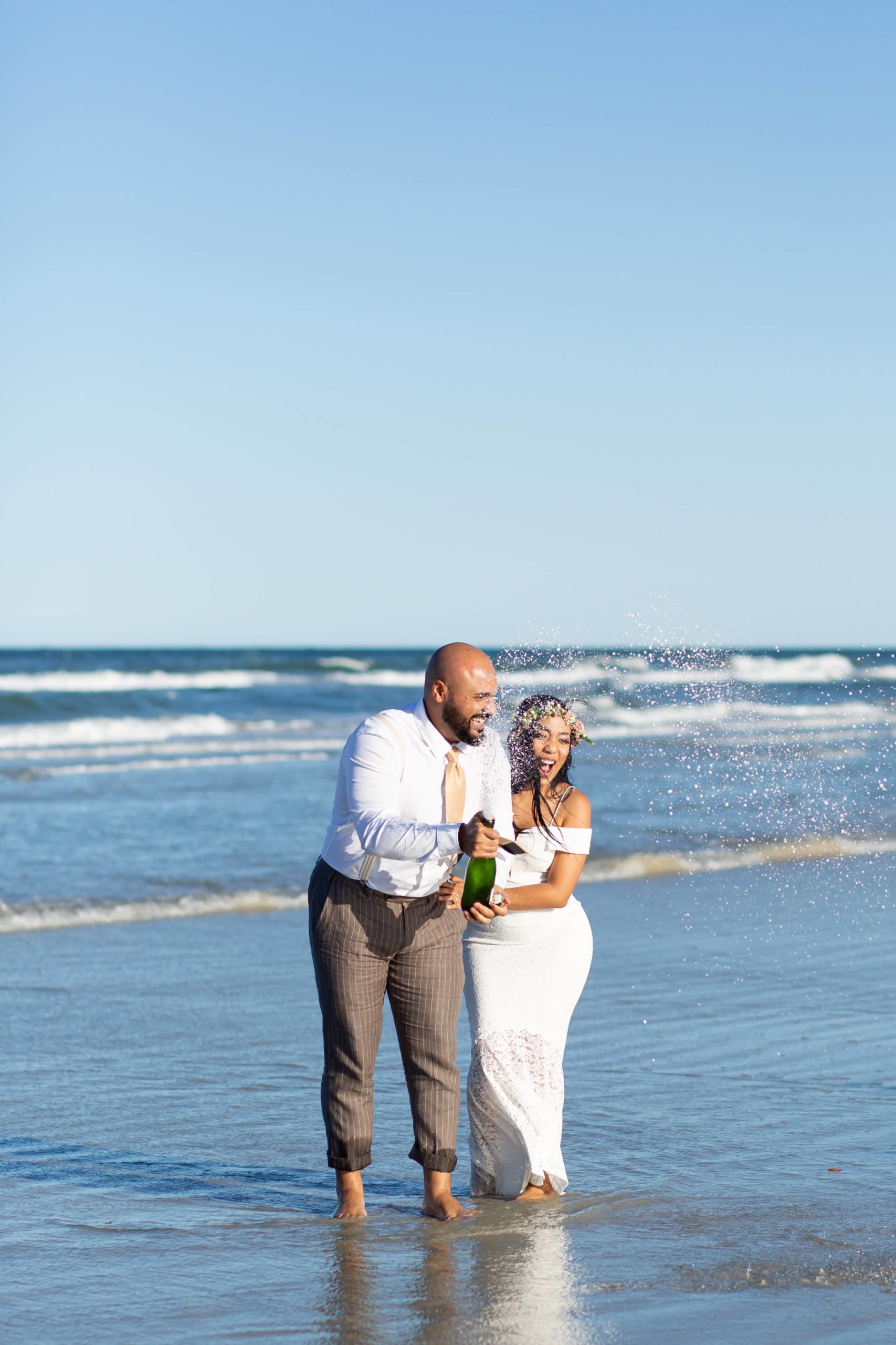Bride & Groom doing a champagne pop in the ocean to celebrate elopement