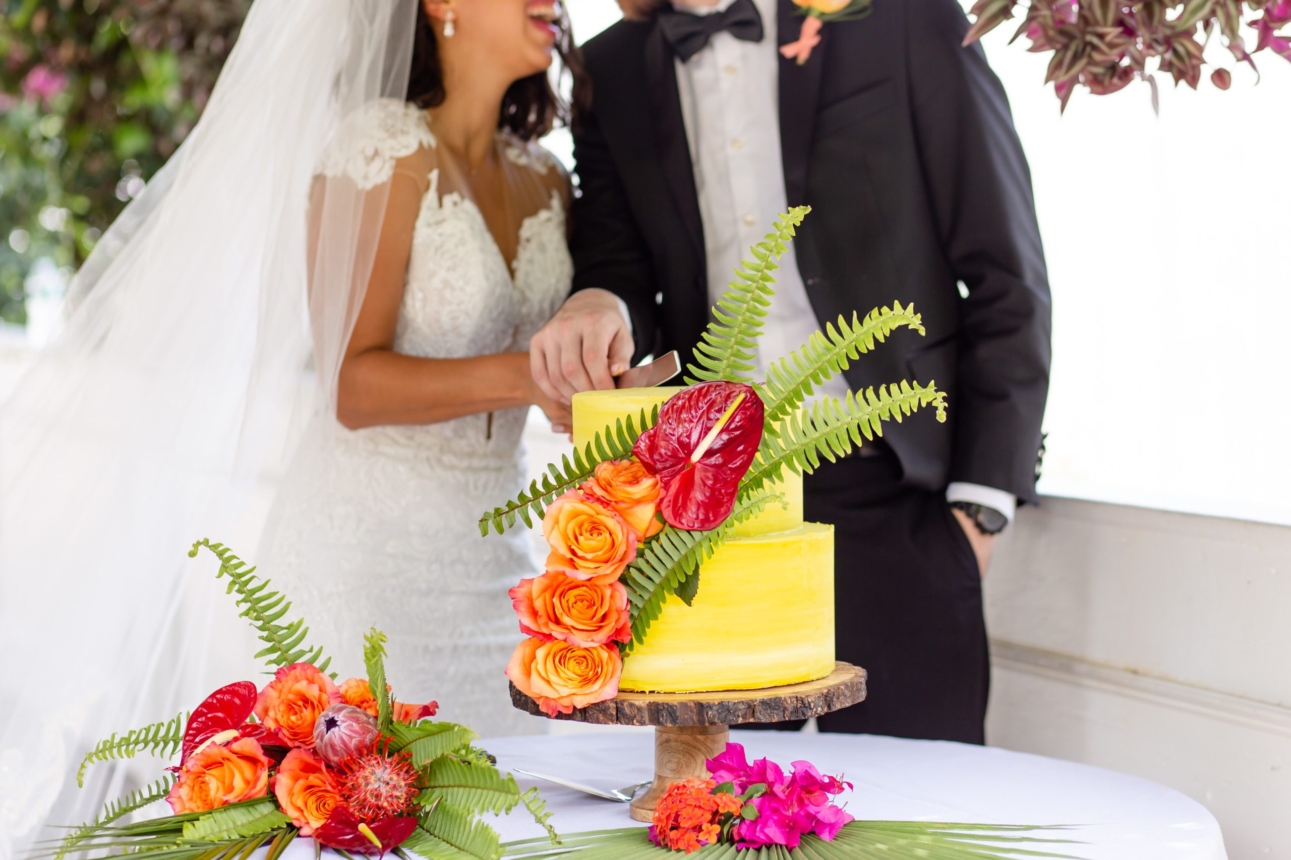 Two tier tropical yellow wedding cake with orange and fuchsia florals 
