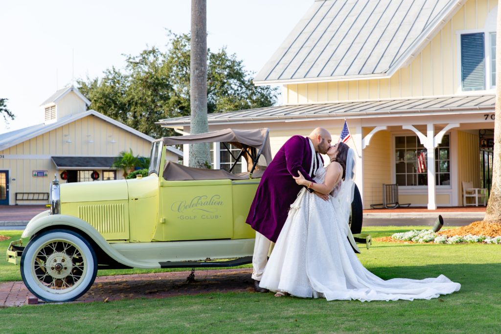 Groom dipping Bride and kissing her in front of old fashioned car at Celebration Golf Club in Celebration, FL