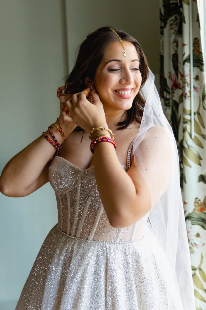 Bride smiling while getting ready and putting on earrings at Celebration Florida Bohemian Hotel