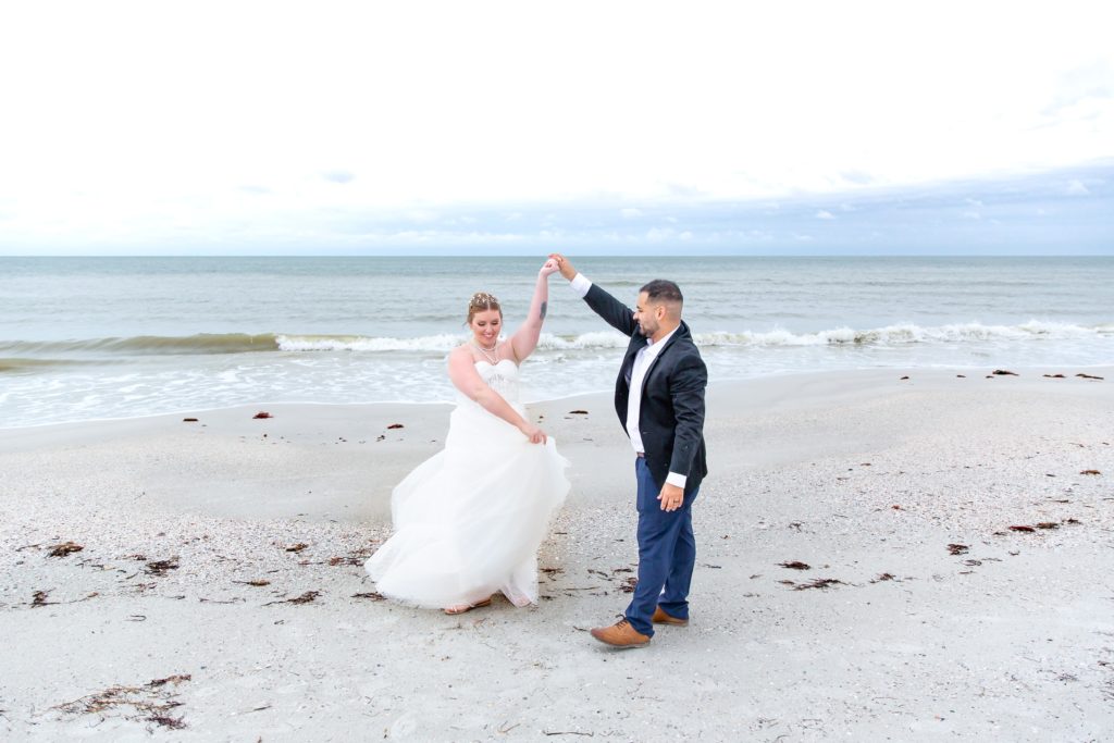 Groom twirling bride on the beach in Treasure Island, FL