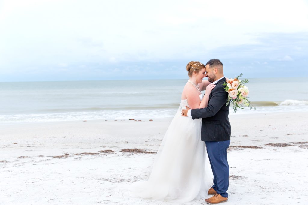 Bride and Groom laughing standing on the beach with bridal bouquet in Treasure Island, FL