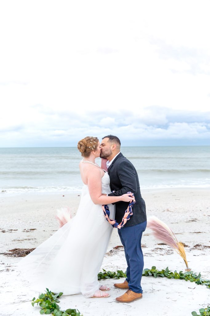 Bride & Groom first kiss on the beach after handfasting ceremony at their elopement