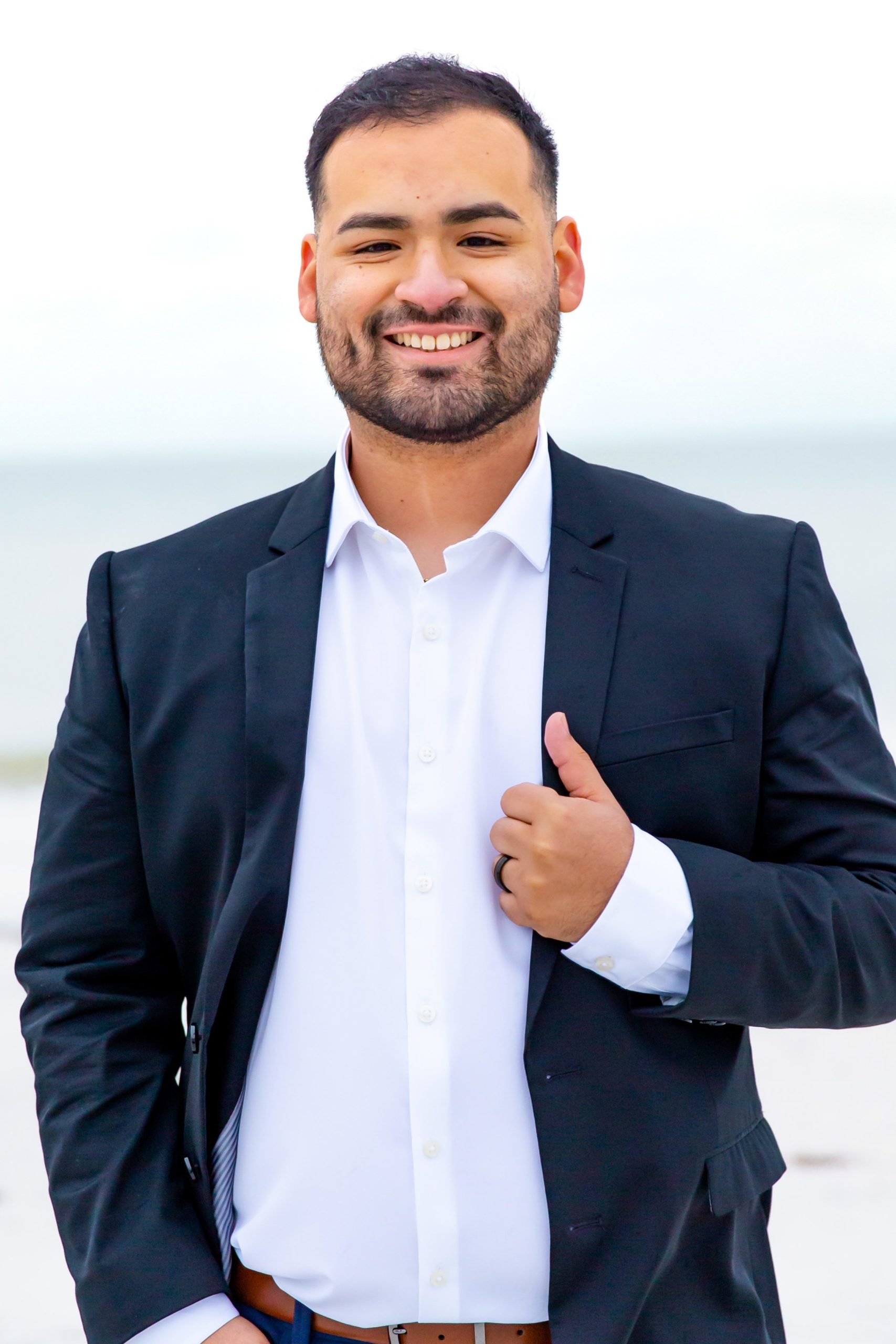 Groom in white shirt with black suit jacket on the beach