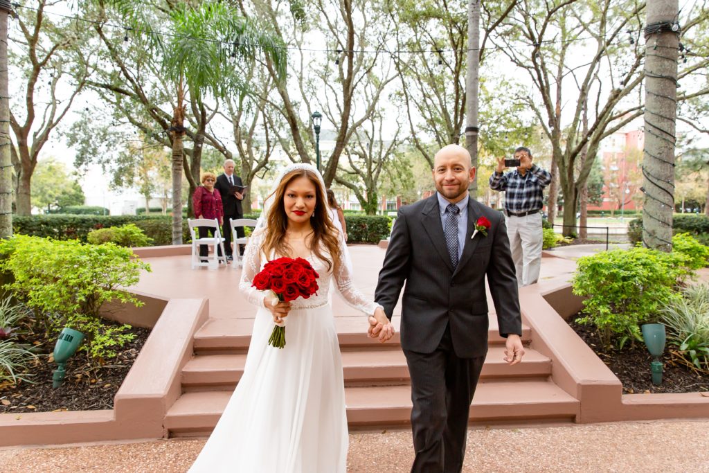 Groom and Bride with red rose bouquet after eloping at Disney Swan Resort in Orlando, FL