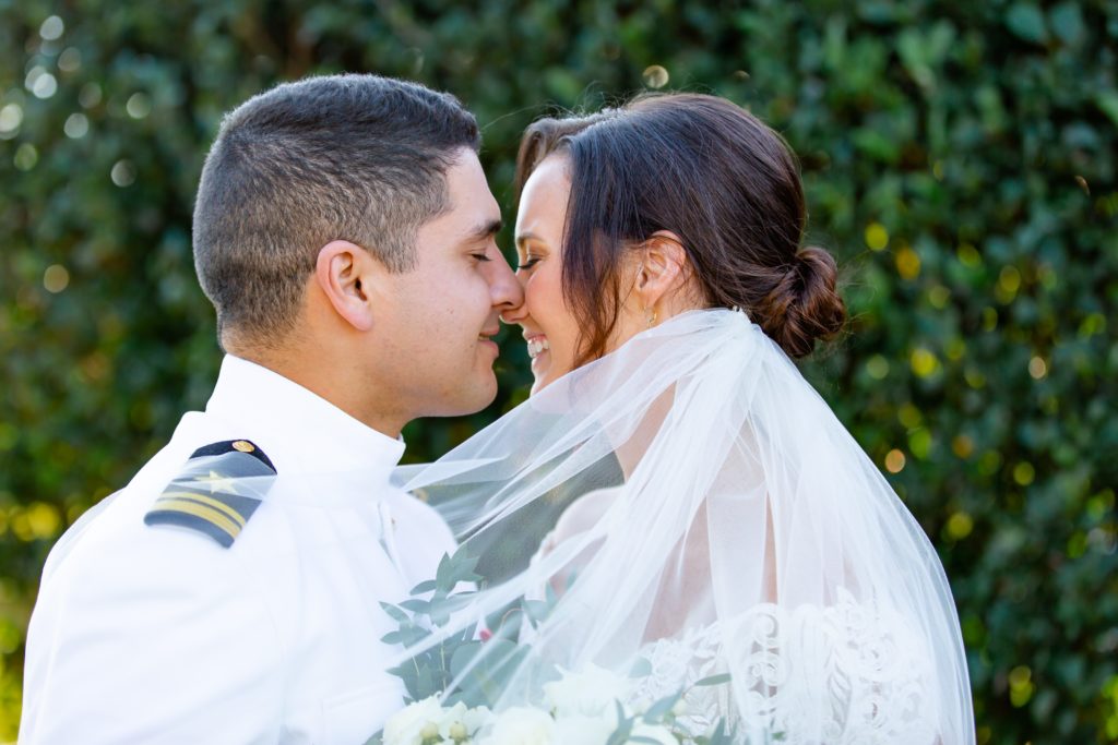 Bride and Groom smiling under veil with ivy wall backdrop at Bramble Tree Estate in Orlando, Florida