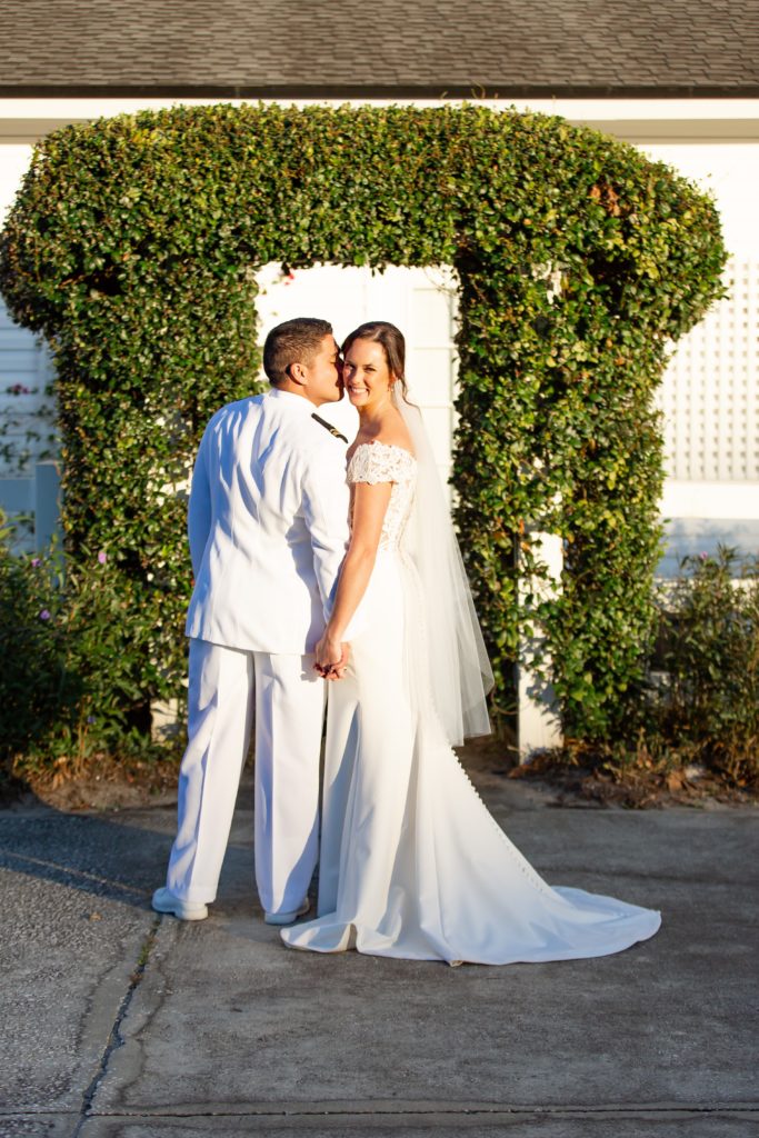 Groom kissing Bride's cheek at sunset standing under ivy arch at Bramble Tree Estate in Orlando, Florida
