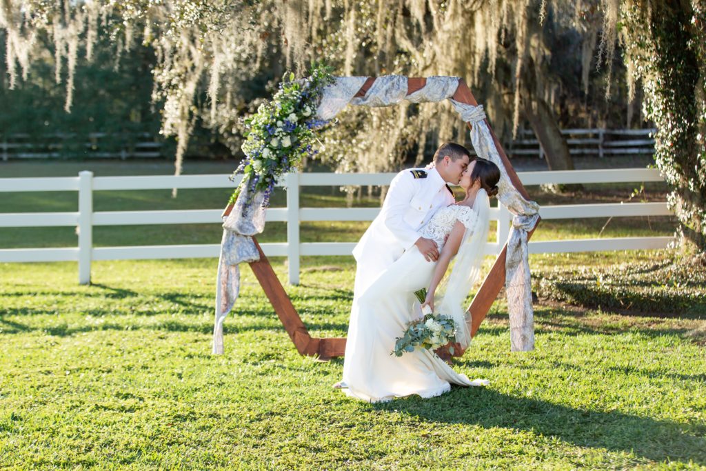 Groom dipping Bride under beautiful live oak tree at sunset in front of wedding arch at Bramble Tree Estate in Orlando, Florida