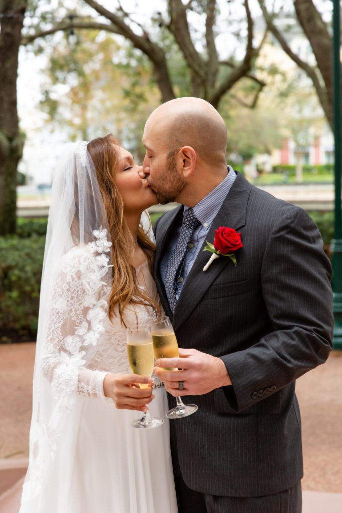 Bride and Groom kissing with champagne after eloping at Disney Swan Resort in Orlando, FL