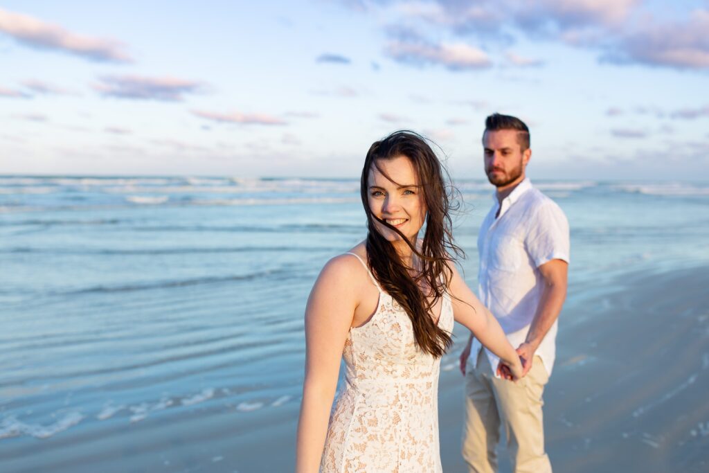 New Smyrna Beach Engagement Photo — Girl leading guy on the beach at sunset