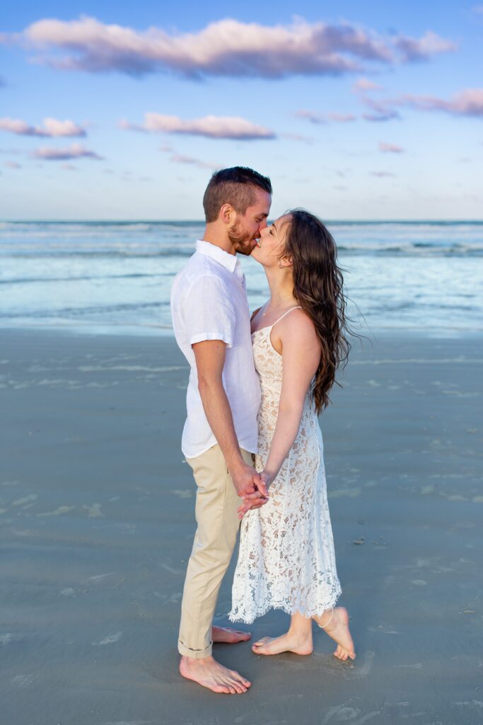 New Smyrna Beach Engagement Photo — Couple kissing on the beach at sunset