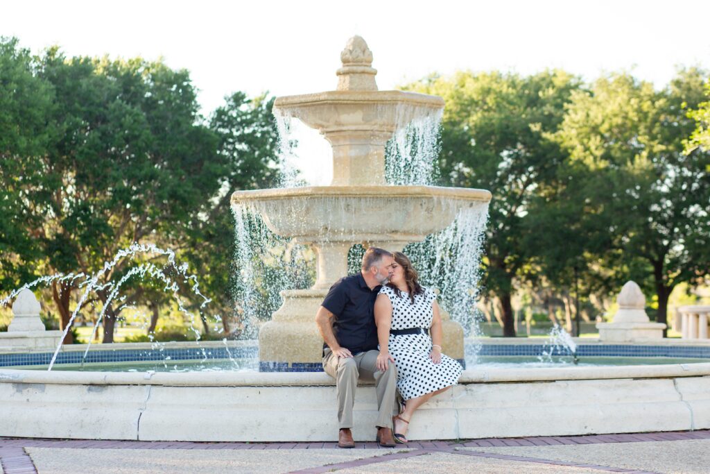 Couple sitting and kissing in front of large fountain at Blue Jacket Park for their Orlando Date Night