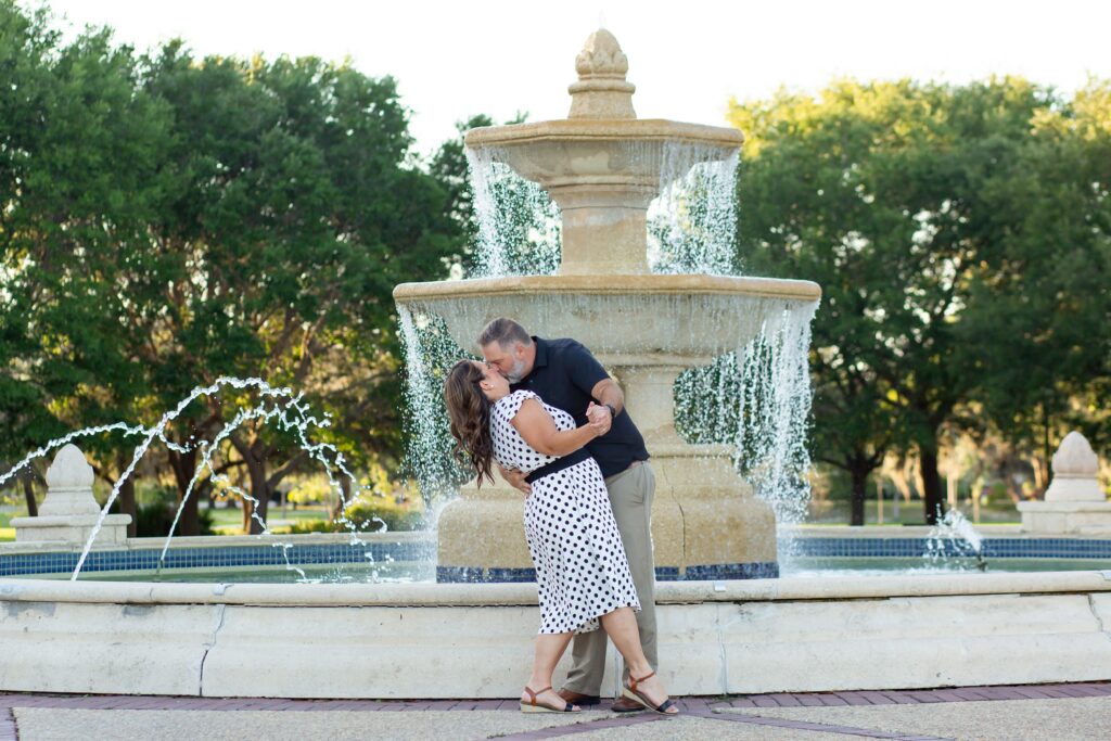 Guy dipping girl and kissing her in front of large fountain at Blue Jacket Park in Orlando for their anniversary photo session