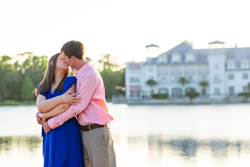 Couple kissing in front of Bohemian Hotel in Celebration Florida Orlando overlooking the water at sunset for their engagement photos