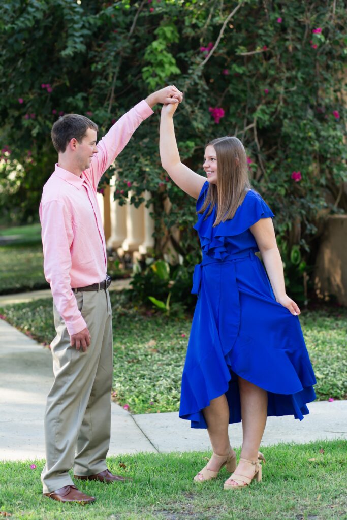 Couple holding hands and dancing in front of Pink Flowers in Celebration Florida Orlando for their engagement photos