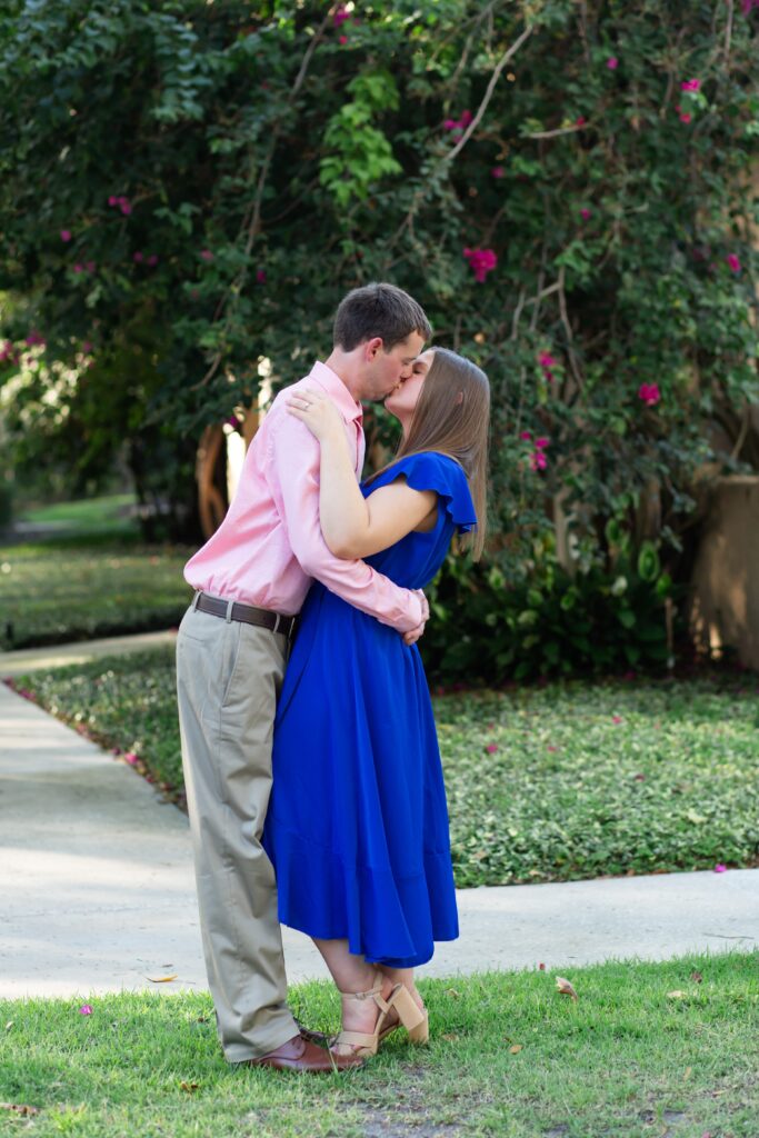 Couple kissing in front of Pink Flowers in Celebration Florida Orlando for their engagement photos